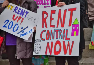 Close-up of "Rent Control Now" sign being held up at a protest.