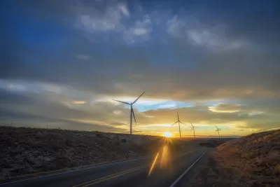 Wind turbines sillhouetted against a sunset sky along roadway in New Mexico