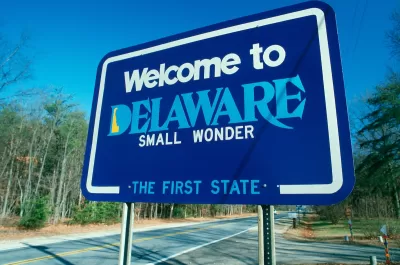 Blue "Welcome to Delaware" roadside sign.