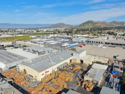 Aerial view of large warehouses in Southern California with hills in background.