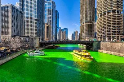 A boat floats on a bright green Chicago River lined by skyscrapers.