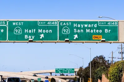 Green and white interstate freeway signs pointing to Hayward and San Mateo and Half Moon Bay exits in Northern California.
