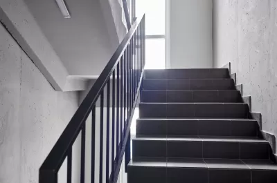 View of plain building staircase with light coming in from window on landing