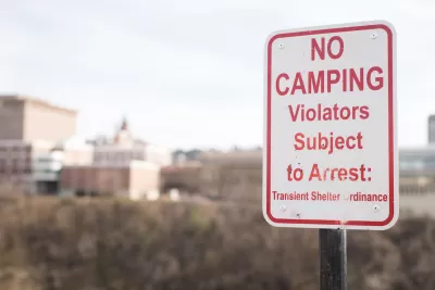 Close-up of red and white "No camping - Violators subject to arrest" sign.