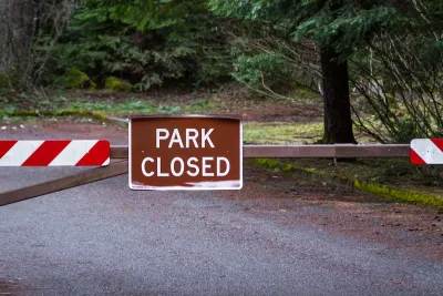 Brown "Park Closed" sign on metal swing gate outdoors.