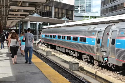 Passengers walking on platform at Boston train station with Amtrak train parked on track.