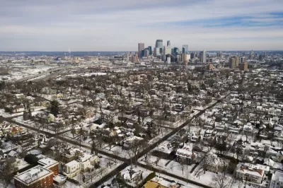 Aerial view of Minneapolis neighborhood and downtown skyline in winter with snow.