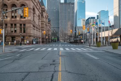 View straight down empty wide street in downtown Toronto, Canada with stoplights during Covid-19 pandemic.