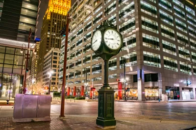 Historic clock on the corner of an intersection in downtown Houston at night.