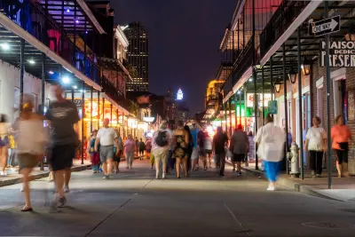 People walking down Bourbon Street in New Orleans at night.