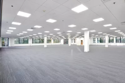 Large empty office building floor with white walls and grey carpeting