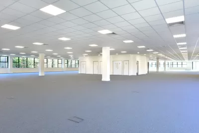 Empty open plan office with gray carpet and white walls