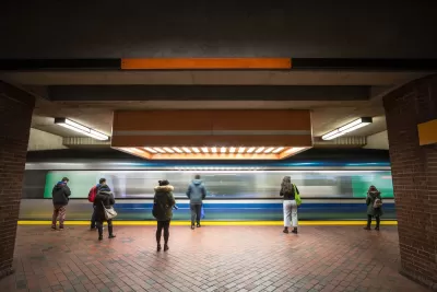 People waiting on subway platform with blurred train passing by.