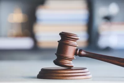 A wooden gavel with gray background filled with a stack of books.