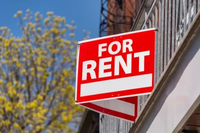 Close-up on red and white "For Rent" sign on building.