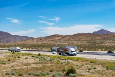 View of trucks on Interstate 15 with desert mountains in background in Southern California.