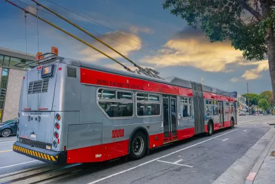 Red and silver Muni trolley bus connected to overhead wires on San Francisco street