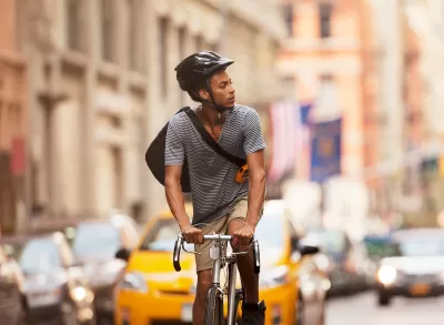 Man riding bicycle wearing black helmet on New York City street.