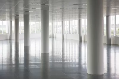 White round pillars in empty office building with windows across all walls and white floors and ceiling.
