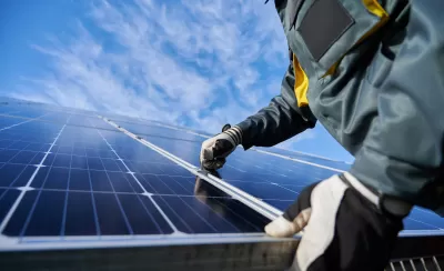 Close-up of technician wearing gloves installing photovoltaic solar panel.