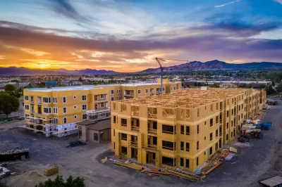 Multifamily wood-frame buildings under construction in Fork, Utah with sunset sky and mountains in background.
