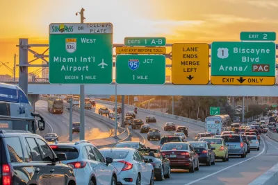 Traffic on Miami freeway with signs for Miami airport and other exits at sunset.