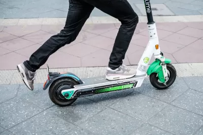 Close-up of person riding green and white Lime e-scooter.