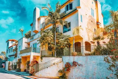 Line of white stucco, multistory luxury homes on street.