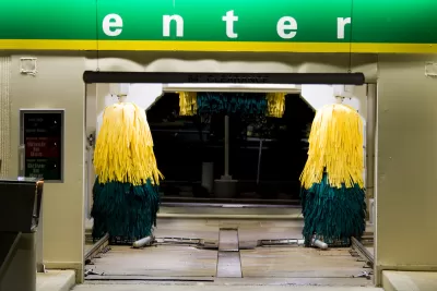 Entrance to a drive-through car wash at night with green 'Enter' sign.