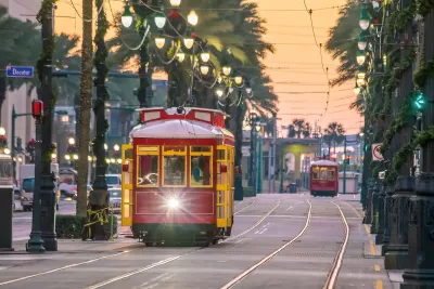 Red and yellow New Orleans streetcar running down street lined with palm trees