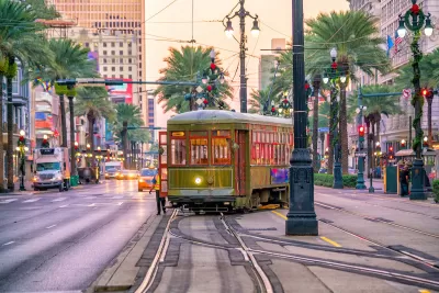 Historic streetcar in middle of street in downtown New Orleans, Louisiana with palm trees and historic lampposts lining the street.
