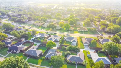 Aerial view of suburb outside Dallas, Texas with large single-family houses with enclosed backyards and green lawns.