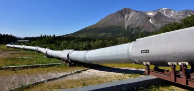 Ground level view of Alaska Pipeline oil pipeline near Prudhoe Bay, Alaska with bare mountains in background.