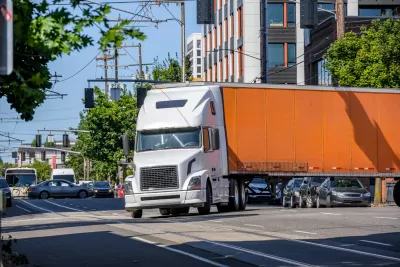 Orange big rig truck turning on a city street