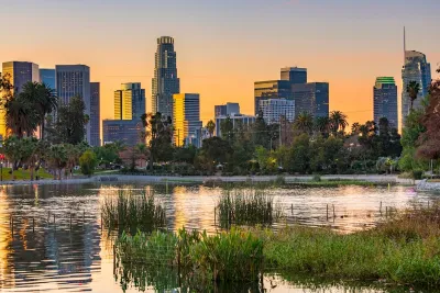 Park pond at sunset with Los Angeles skyline in background.