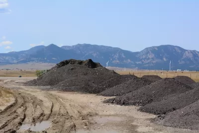 Piles of recycled asphalt and bitumen to be recycled for making roads with Rocky Mountains in background.
