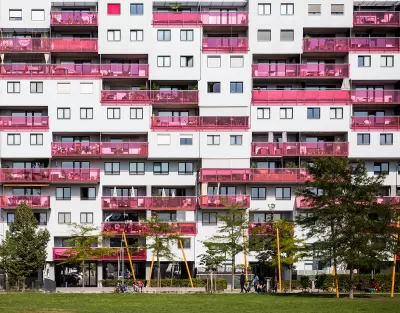 Multistory apartment building facade in Vienna, Austria with pink glass balconies.