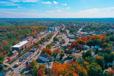 Aerial view of small New Hampshire town with brick buildings and fall foliage.