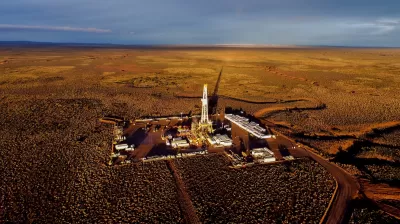 Aerial view of fracking equipment in desert-type plain at golden hour.