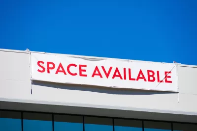 White banner with red "SPACE AVAILABLE" text hanging at top of white office building.