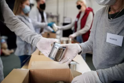 Close-up of people wearing white gloves and Covid-19 masks exchanging unlabeled can of food at food bank