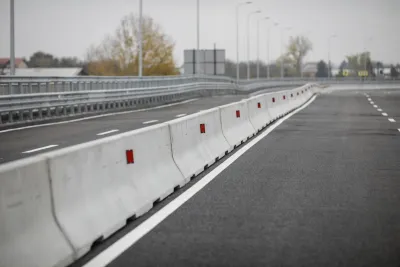 Row of concrete Jersey barriers running down the middle of a multi-lane road.