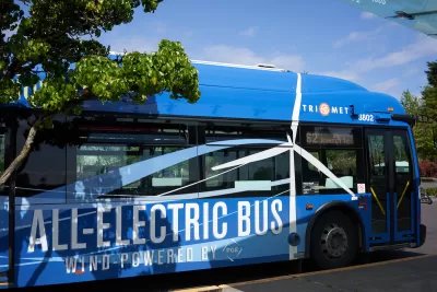Blue electric bus labeled with 'All-Electric Bus Wind Powered by PGE' in white in Tigard, Oregon.