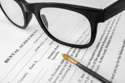 Close-up of rental agreement with pen and black-rimmed glasses.