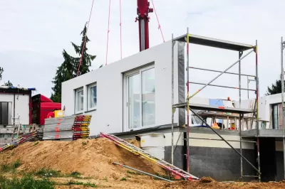 White modular home being built on dirt mound