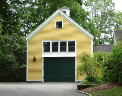 Yellow converted garage with green door and white-framed windows.