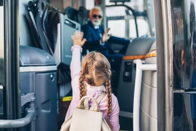 Young girl with pigtail braids boarding bus with blurred bus driver in driver's seat in background