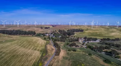 Aerial view of small community among green agricultural fields and wind turbines in Solano County, Northern California.