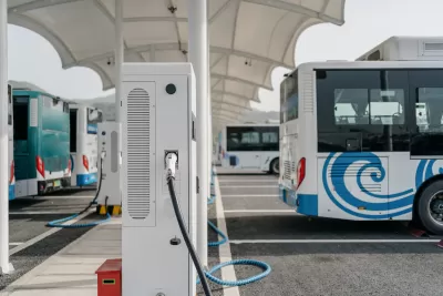 White electric tranasit bus plugged into a charging station