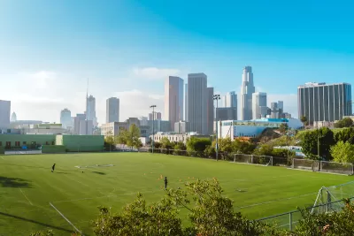 Green grass soccer field with Los Angeles skyline in background.